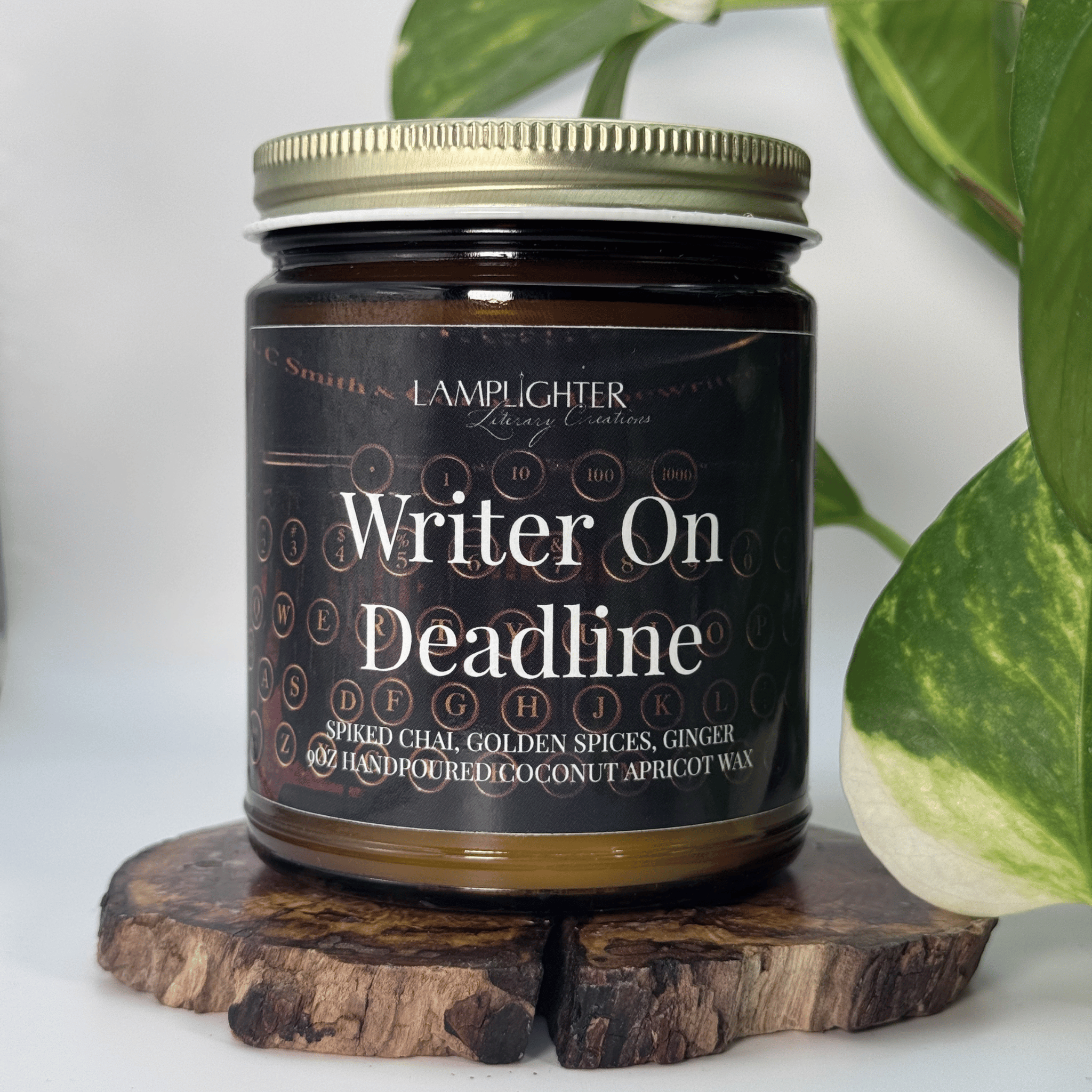 Candle jar labeled 'Writer On Deadline' on a wooden stand with a plant in the background